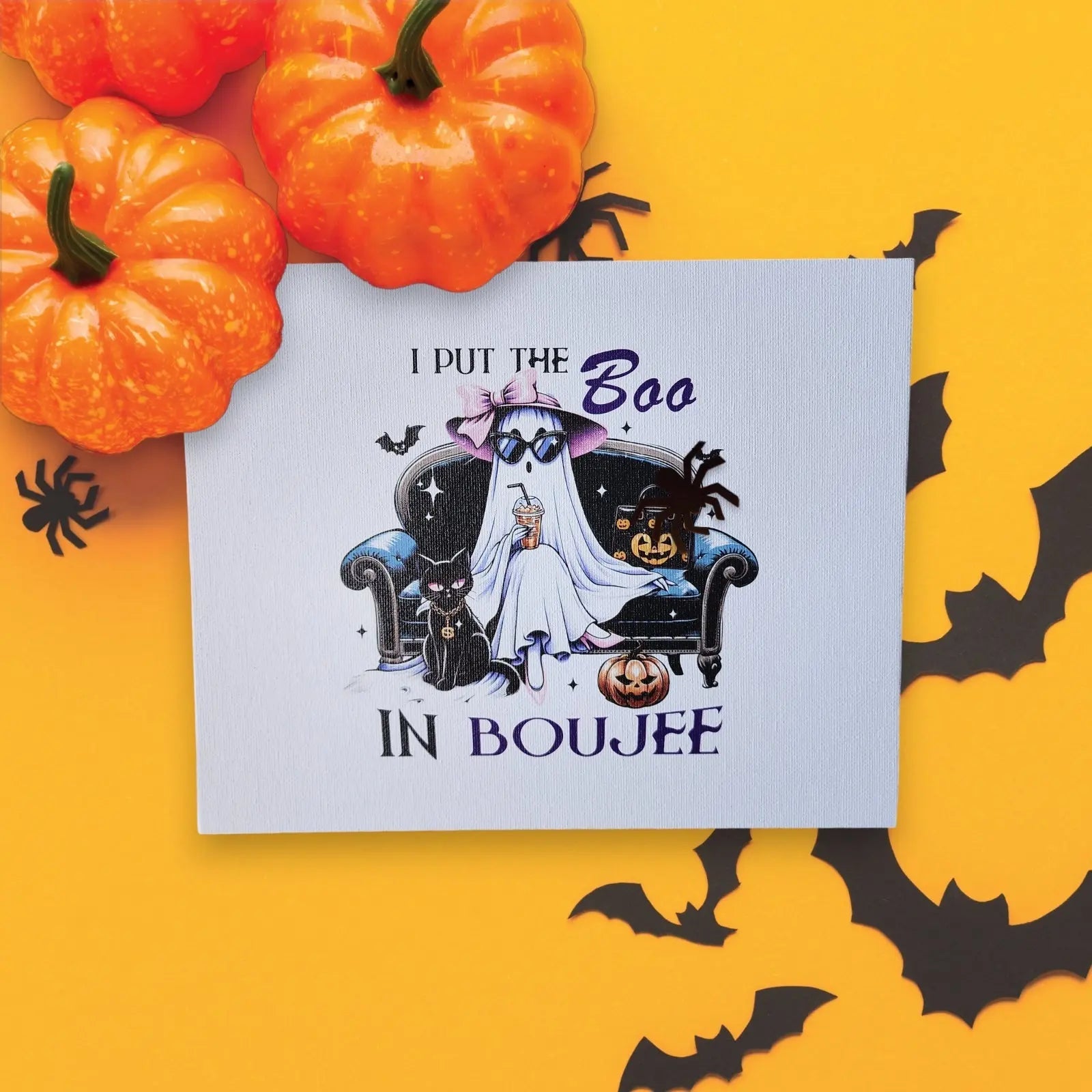 Mirabilia Boutique's "Funny Halloween Sign: I put the Boo in Boujee" is a Halloween-themed card that's perfect for any ghost enthusiast. It features a charming ghost wearing a purple bow, sitting on a couch with a black cat, pumpkin, and bat. The caption humorously reads, "I put the Boo in Boujee." Surrounded by miniature pumpkins and bat cutouts on a yellow background, this sign makes for delightful Halloween decor.