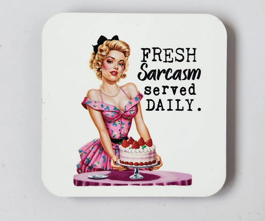 A vintage-style illustration of a retro housewife in a pink dress with a bow in her blonde hair, holding a cake with strawberries, is accompanied by the text "FRESH Sarcasm served DAILY." on a white background. This charming design appears on the Fresh Sarcasm Served Daily Retro Magnet from Mirabilia Boutique, perfect for adding some kitchen humor to your decor.