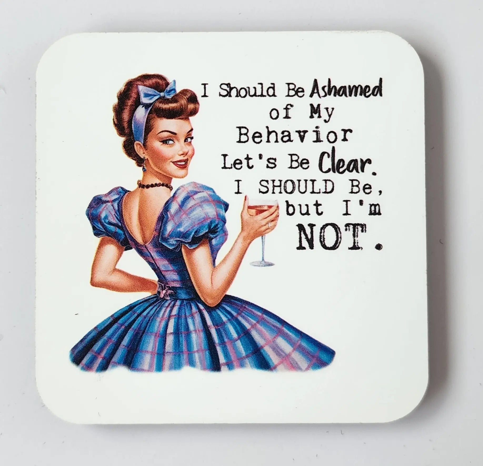 A retro-style illustration of a woman in a blue dress holding a cocktail glass, smiling. Text beside her reads, "I should be ashamed of my behavior. Let's be clear. I should be, but I'm not." This snarky retro magnet, named "I Should Be Ashamed of My Behavior But I'm Not," is perfect for your fridge! Available from Mirabilia Boutique.