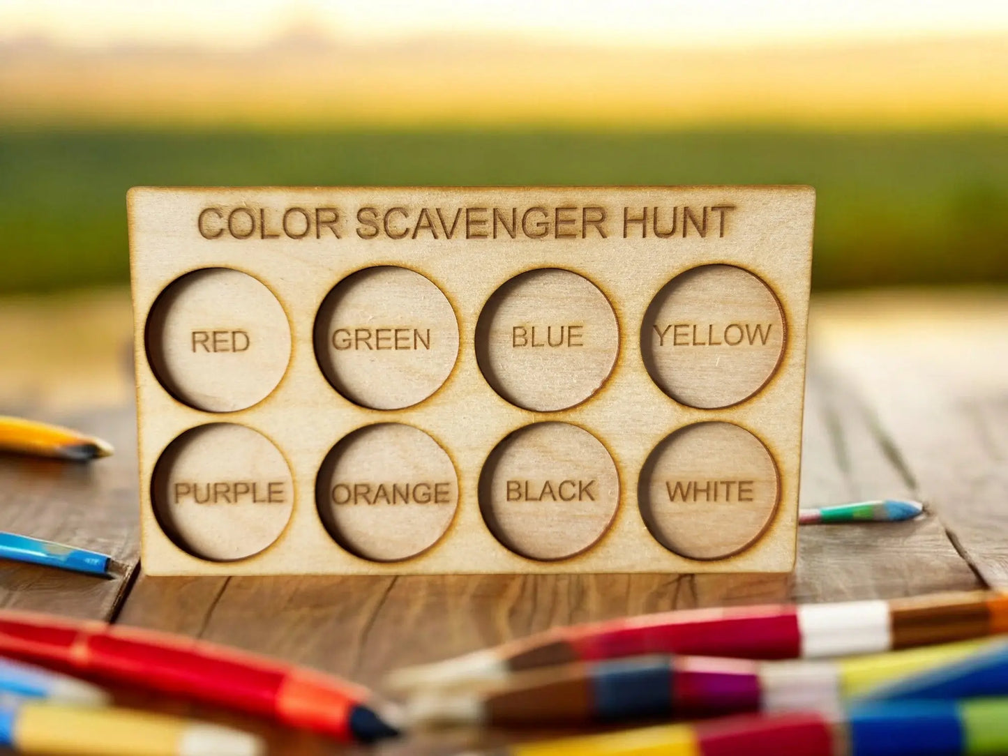 The "Exciting Color Scavenger Hunt Game for Kids' Outdoor Fun" by Mirabilia Boutique features a wooden board with eight circular slots displaying vibrant colors such as red, green, and blue. This eco-friendly outdoor toy includes scattered colored pencils, offering a delightful way to explore hues on a rustic wooden surface.