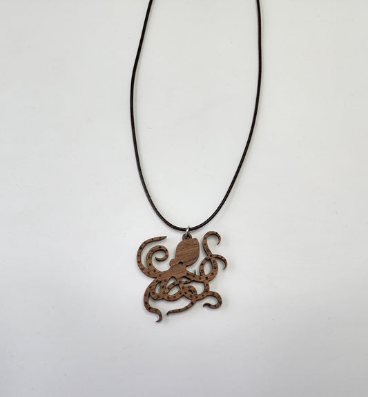 The Wood Octopus Pendant by Mirabilia Boutique features a handmade, intricately carved octopus with detailed tentacles on a black cord necklace, set against a plain white background, capturing nautical elegance.