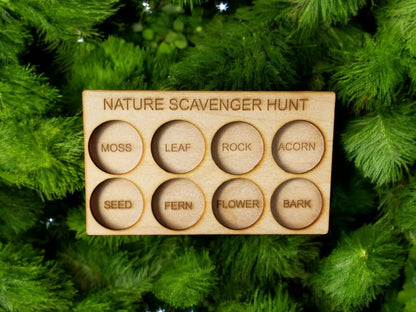 Discover the eco-friendly "Nature Scavenger Hunt for Kids: Fun Outdoor Adventure Game" by Mirabilia Boutique, a wooden board with circular cutouts perfect for collecting treasures such as moss, leaves, and acorns. This delightful outdoor toy fits beautifully against a backdrop of lush green foliage.