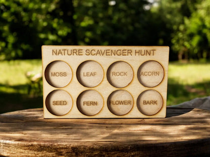 Mirabilia Boutique's "Nature Scavenger Hunt for Kids: Fun Outdoor Adventure Game" offers an eco-friendly wooden board featuring eight circular, labeled sections: moss, leaf, rock, acorn, seed, fern, flower, and bark. Ideal as an outdoor toy, it is displayed on a wooden surface against a blurred green backdrop.